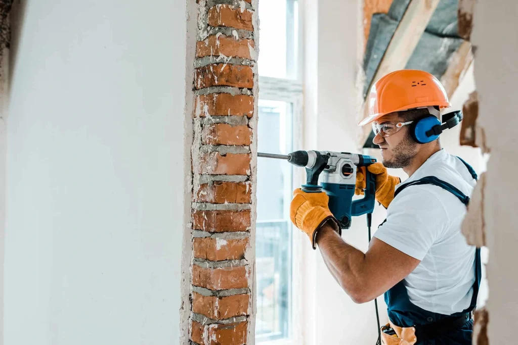 Man in hard hat drilling through a wall